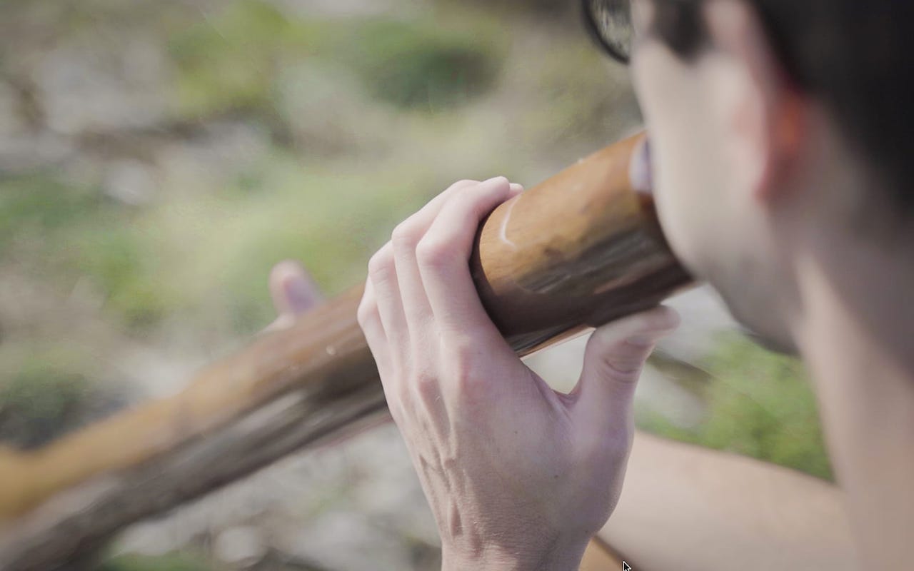 jouer de didgeridoo de dos en train de jouer