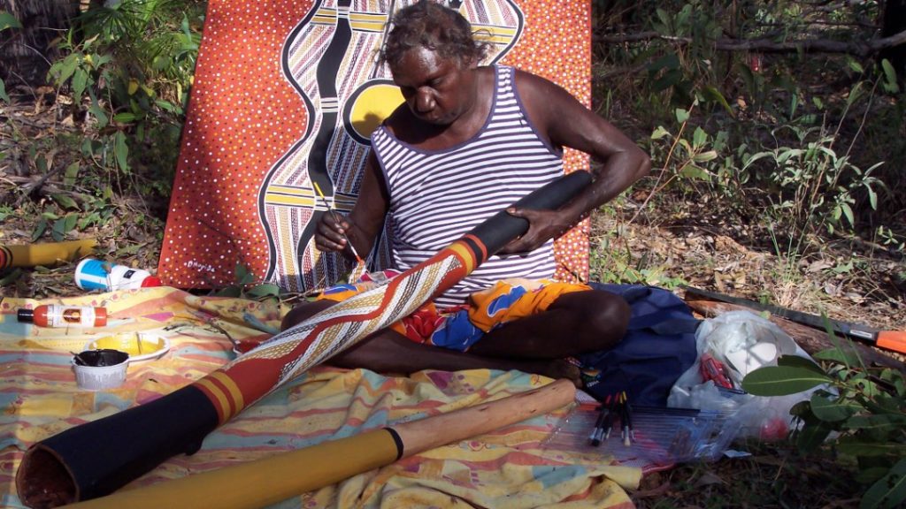 Une femme Aborigène peint un didgeridoo traditionnel