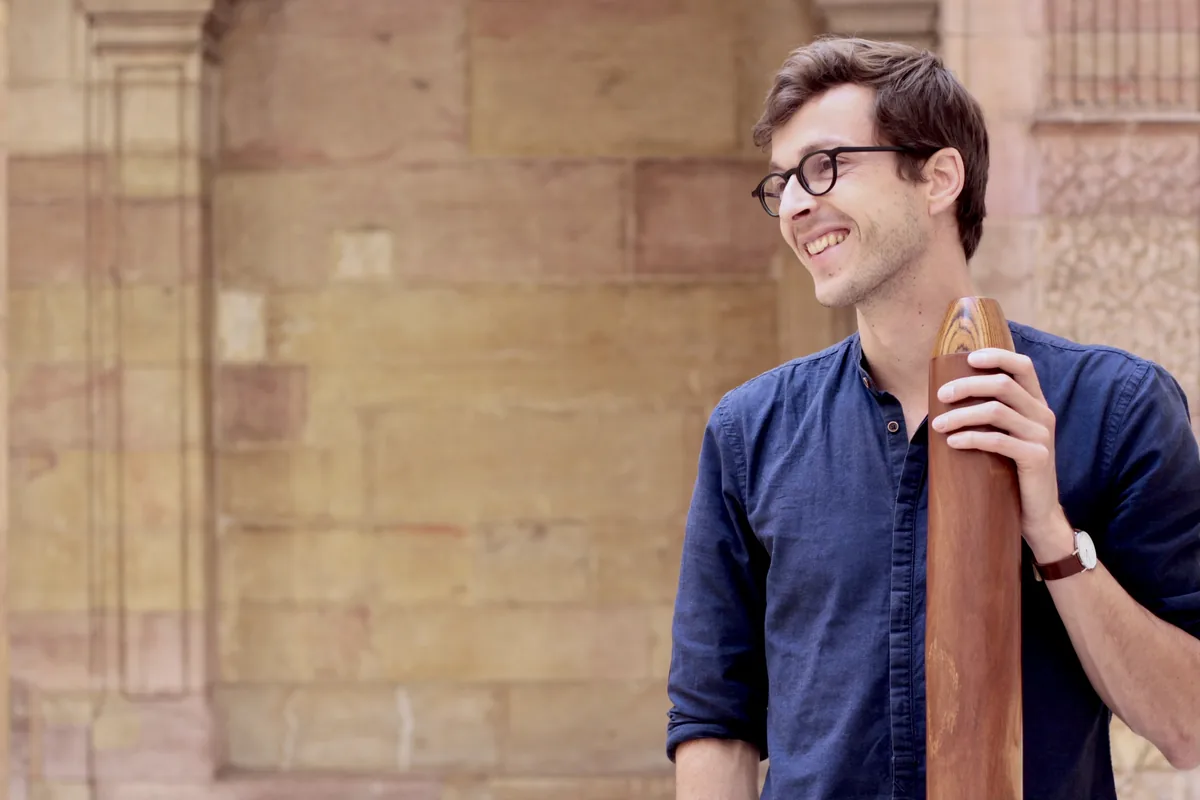 Gauthier Aubé, souriant, un didgeridoo à la main